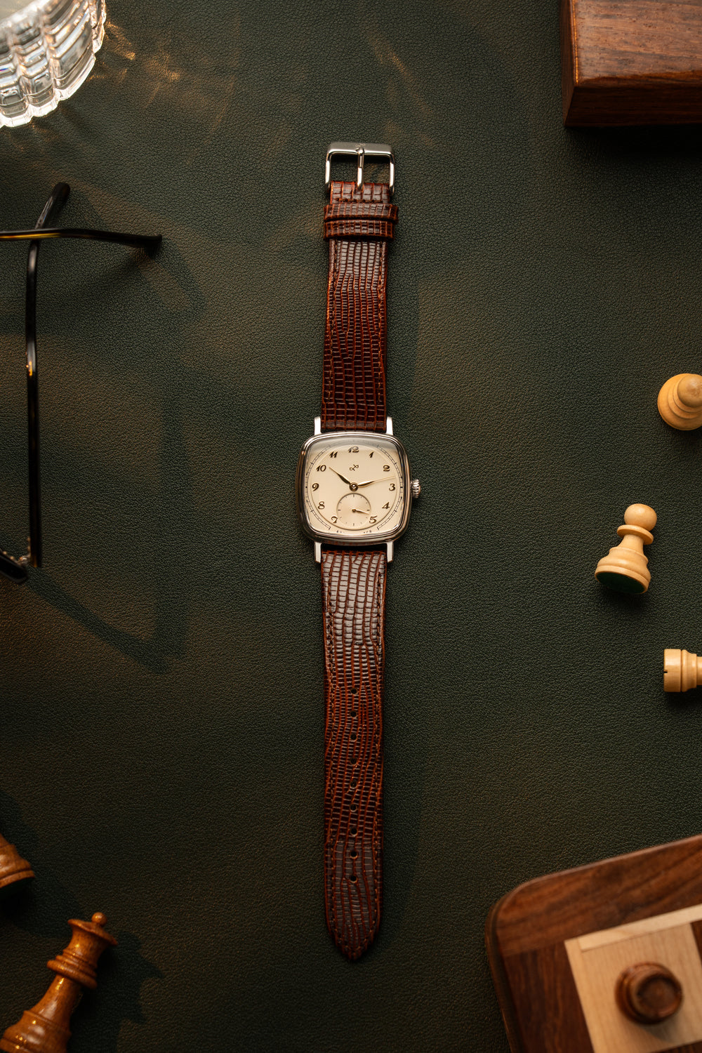 1954 Amalfi Mechanical by AV86 with cushion case, mechanical movement, vintage dial, and textured brown leather strap displayed on dark surface with chess pieces