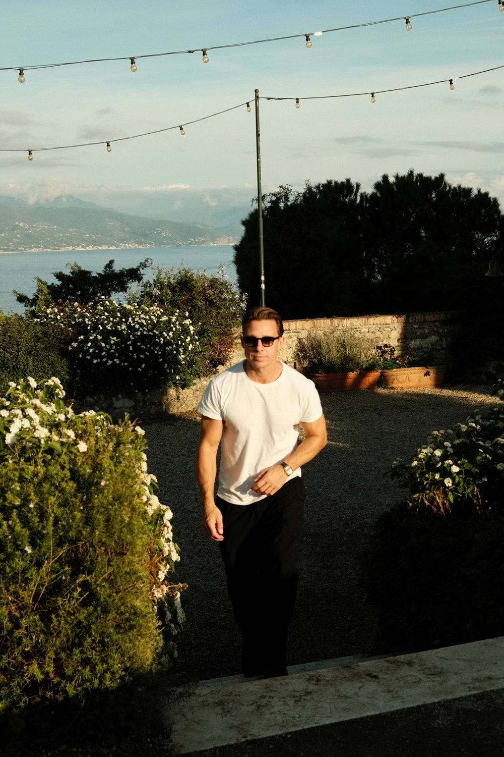 1954 Amalfi Mechanical by AV86 worn with casual attire in tranquil garden terrace with coastal mountains and string lights at dusk