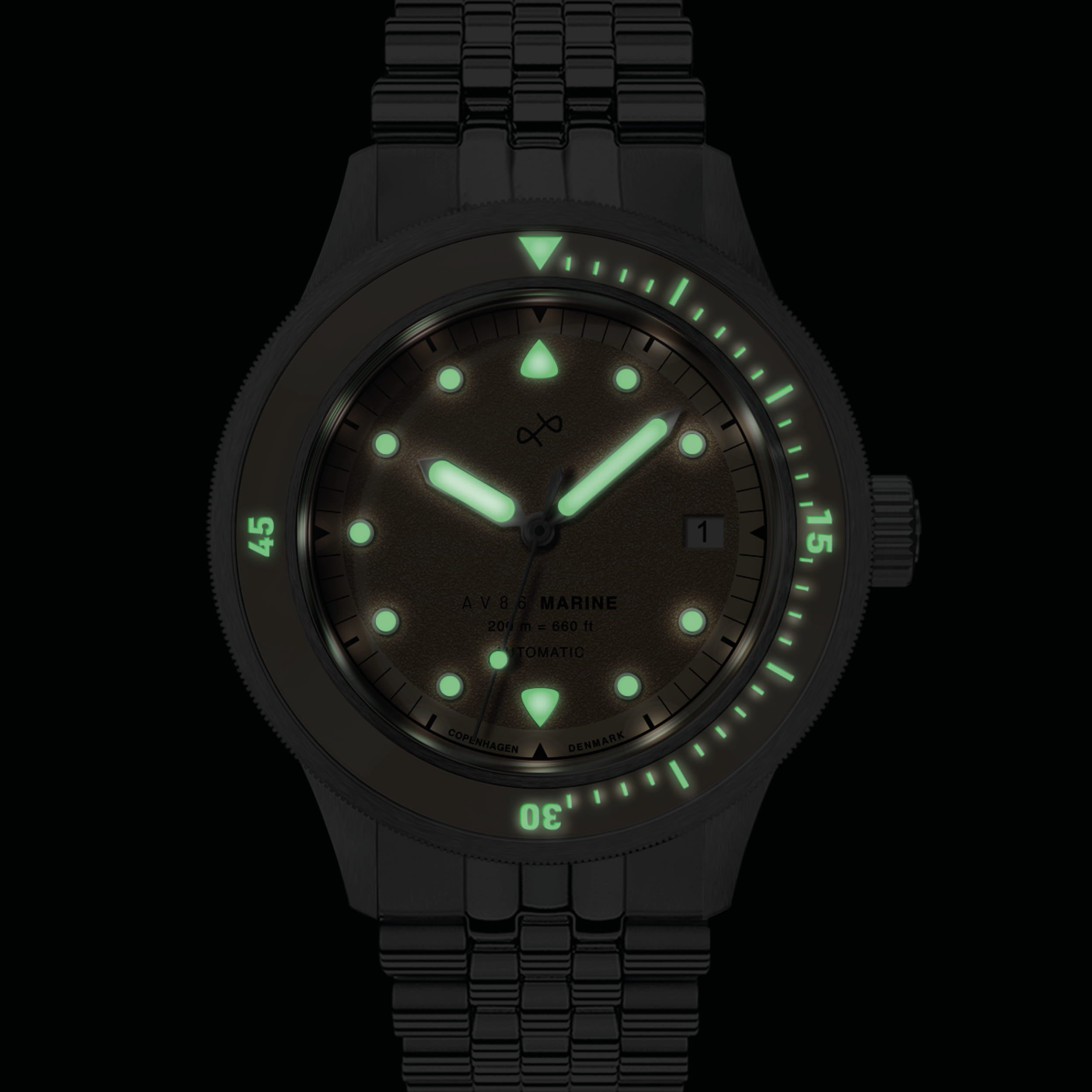 1956 Marine Automatic, Steel / Sand watch by AV86 showing glowing hands and markers in low light with a steel bracelet.