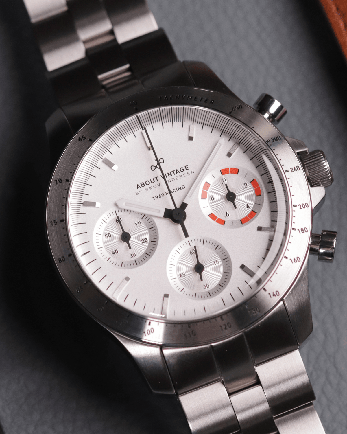 AV86의 1960 Racing Chronograph. 빈티지 스타일의 다이얼, 타키미터 베젤, Sapphire Crystal, 스테인리스 스틸 브레이슬릿 스트랩을 갖추고 있습니다.
