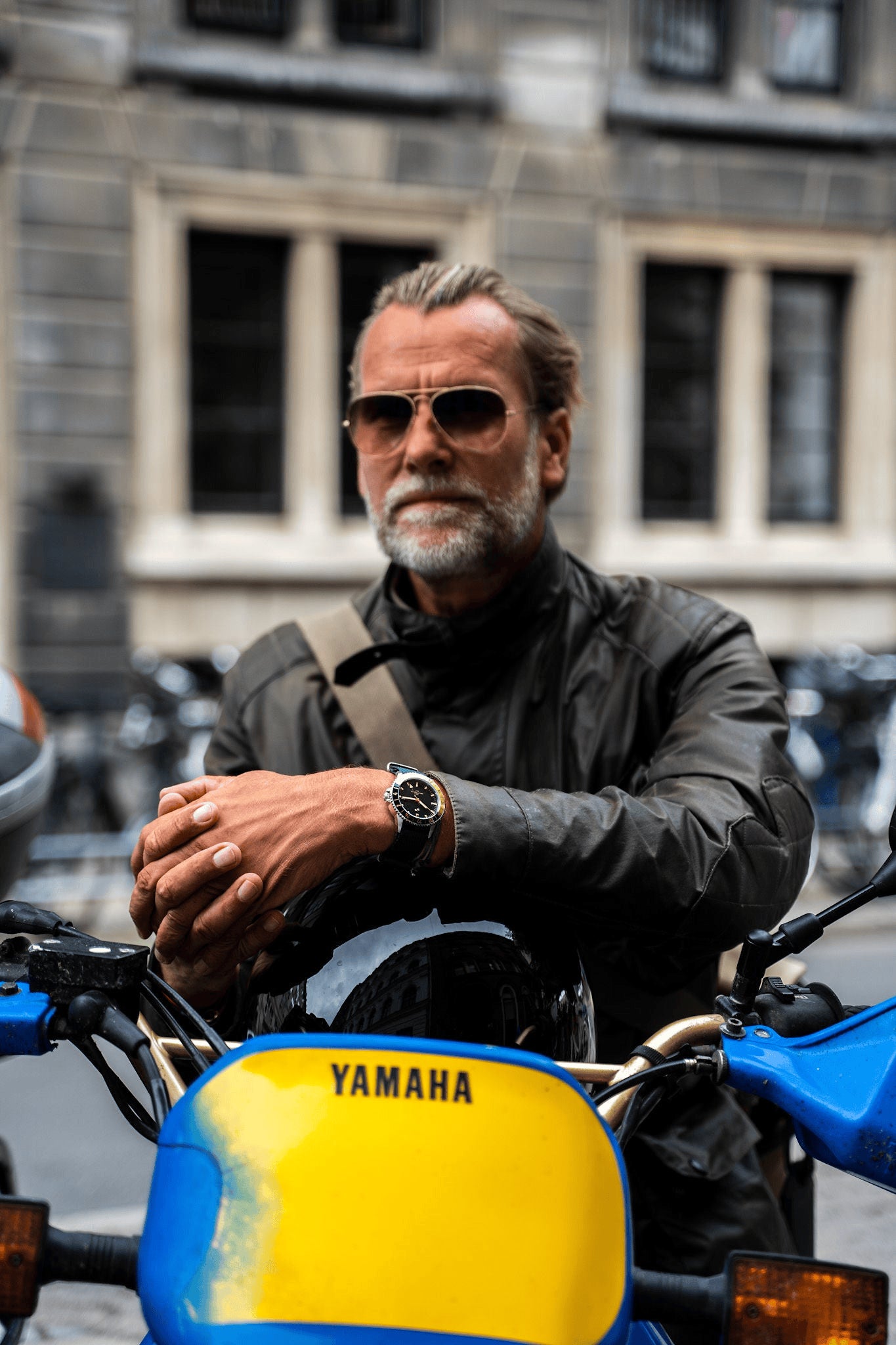 Montre GMT Haagen de 1970, fabrication suisse par AV86, de style vintage, dotée d'un verre saphir et d'un bracelet en cuir noir, portée au poignet par un motard sur une Yamaha