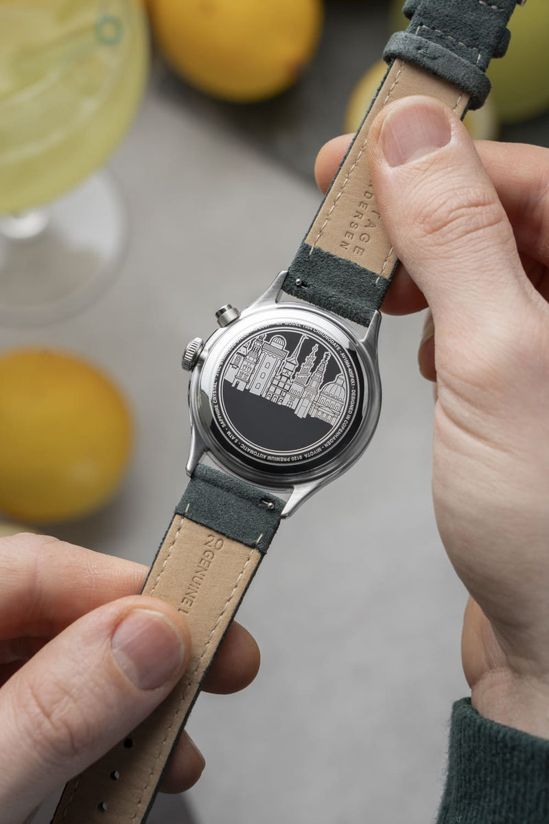 1564 Chronodate Automatic by AV86 showcasing engraved case back with cityscape motif and leather strap details