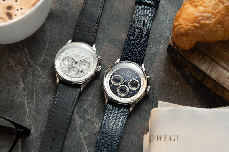 1564 Chronodate Automatic by AV86 presents two vintage-inspired automatic chronographs with textured leather straps, sapphire crystals, multi-function subdials, and polished cases, reflecting refined Danish horological craftsmanship alongside a casual breakfast setting that evokes Nordic minimalism and understated luxury.
