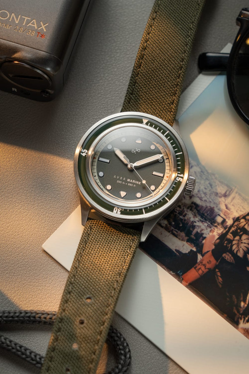 1956 Marine by AV86 vintage-inspired diver with sapphire crystal, compass bezel, and green fabric strap in natural light setting