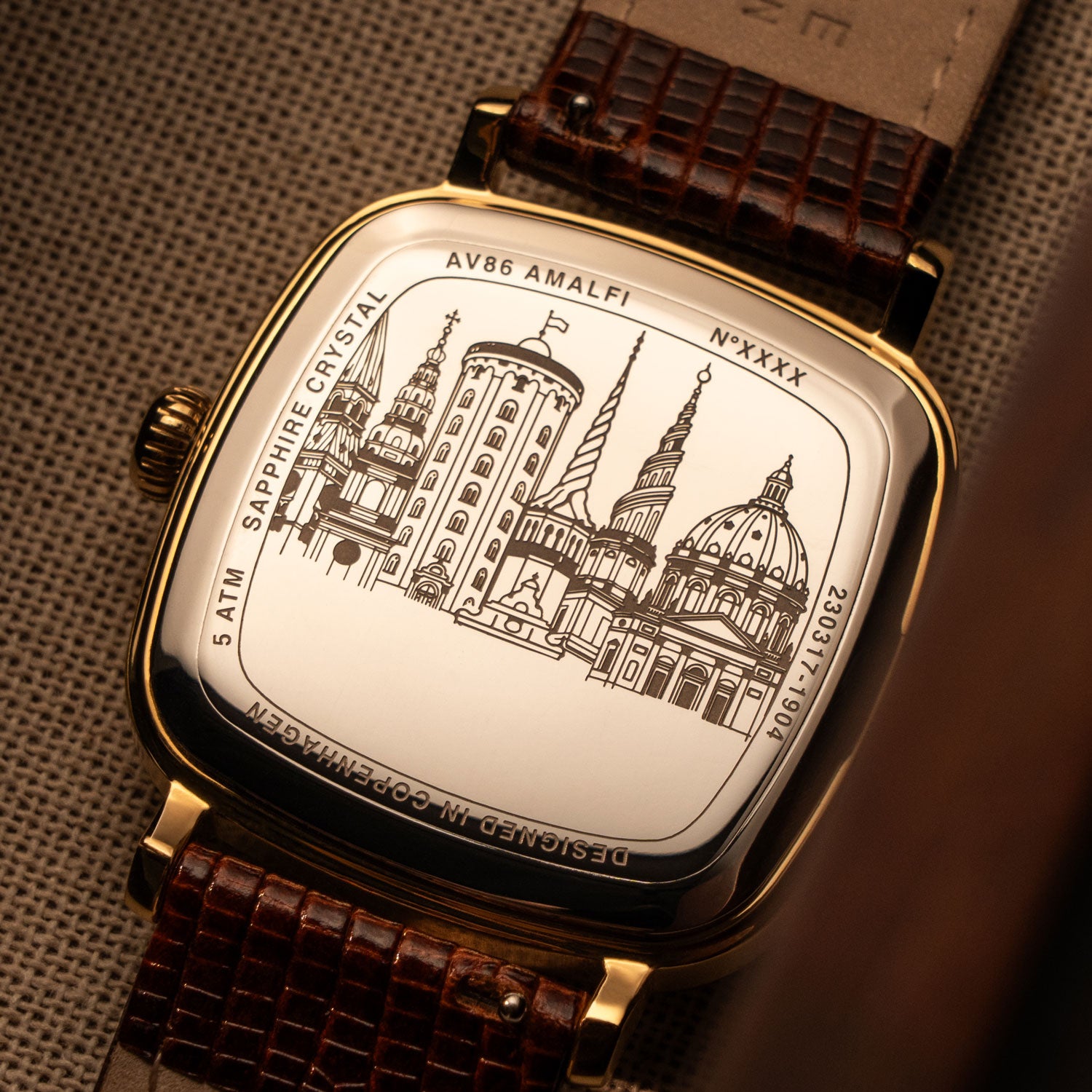 Case back engraving of Copenhagen cityscape on AV86 Amalfi watch with curved sapphire crystal and textured leather strap.