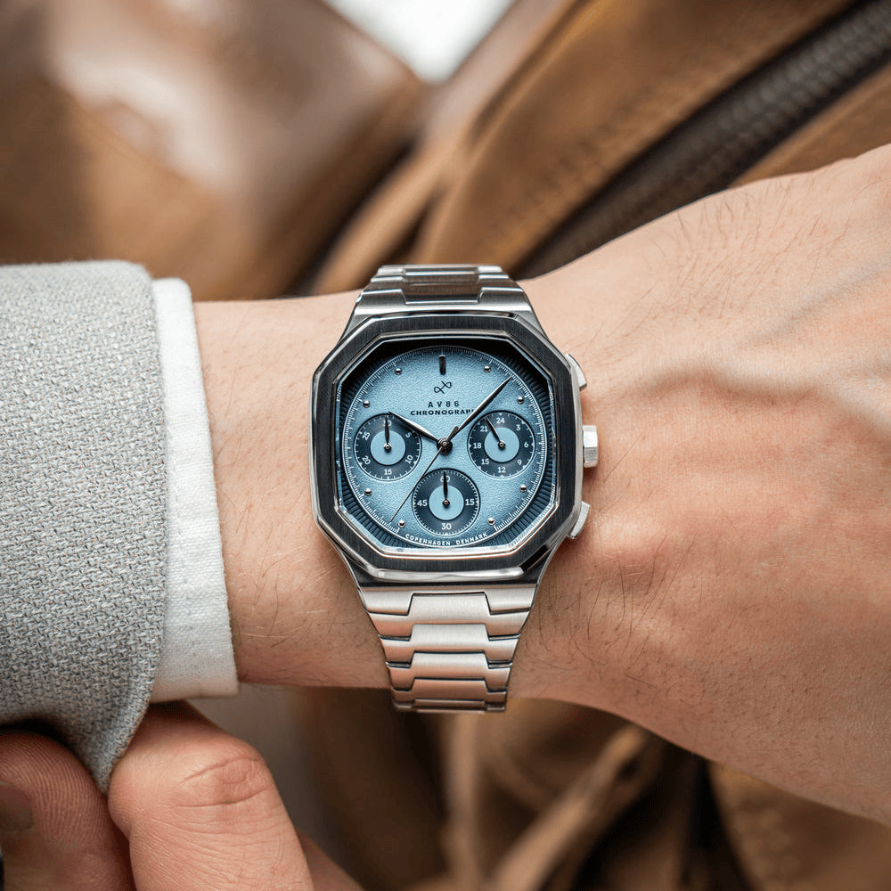 AV86의 1904 Chronograph 럭셔리 시계로, 각진 케이스, Sapphire Crystal, 크로노그래프 서브 다이얼, 그리고 광택 처리된 메탈 브레이슬릿 스트랩을 갖추고 있습니다.