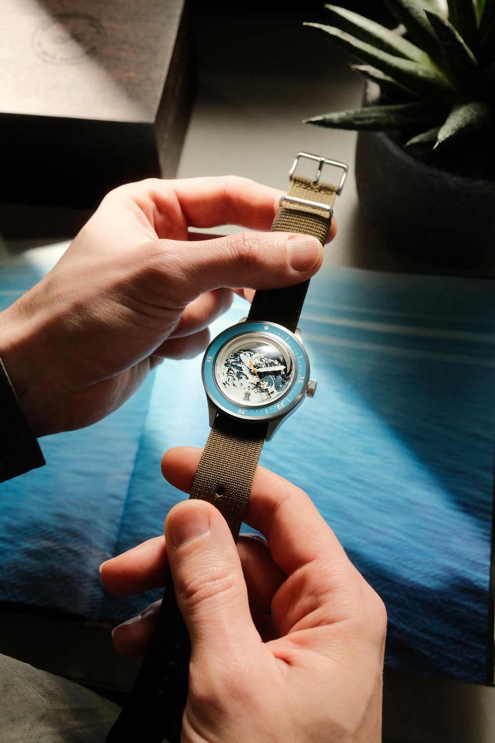 Uhr „Hands holding Earthrise WWF Partnership“, Automatik / Edition 2026 von AV86 mit Stoffarmband, strukturiertem Zifferblatt und blauer Lünette.