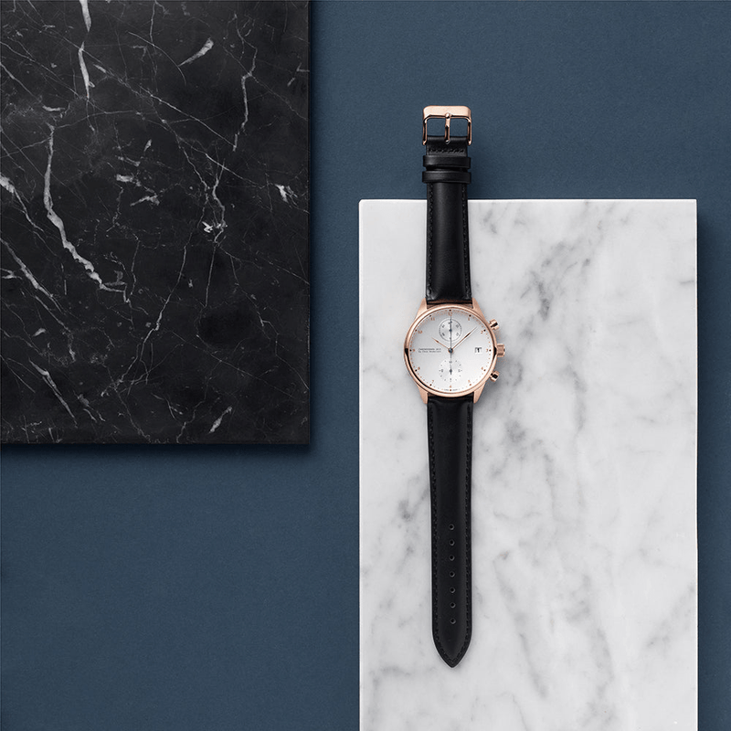 Chronographe 1815, or rose / blanc par AV86 : chronographe de luxe doté d'un verre saphir, d'un boîtier en or rose et d'un bracelet en cuir noir, sur fond marbré