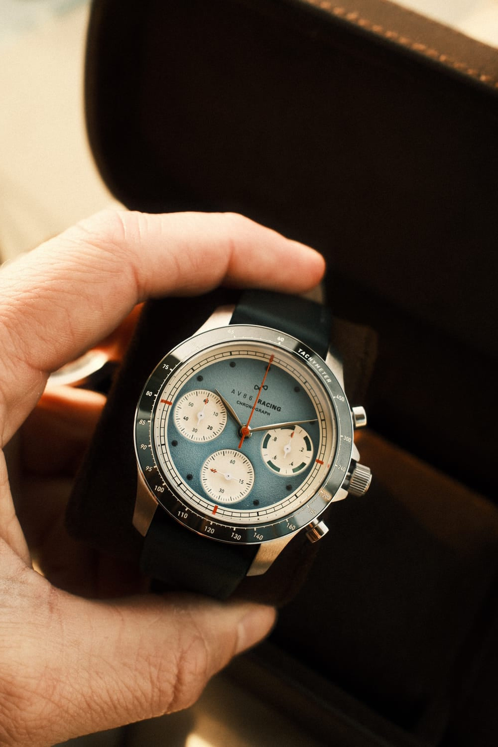 AV86 1960 Racing Chronograph, Steel / Sky Blue & Green quartz chronograph with pale blue dial, three subdials, tachymeter bezel, and black strap held in a case