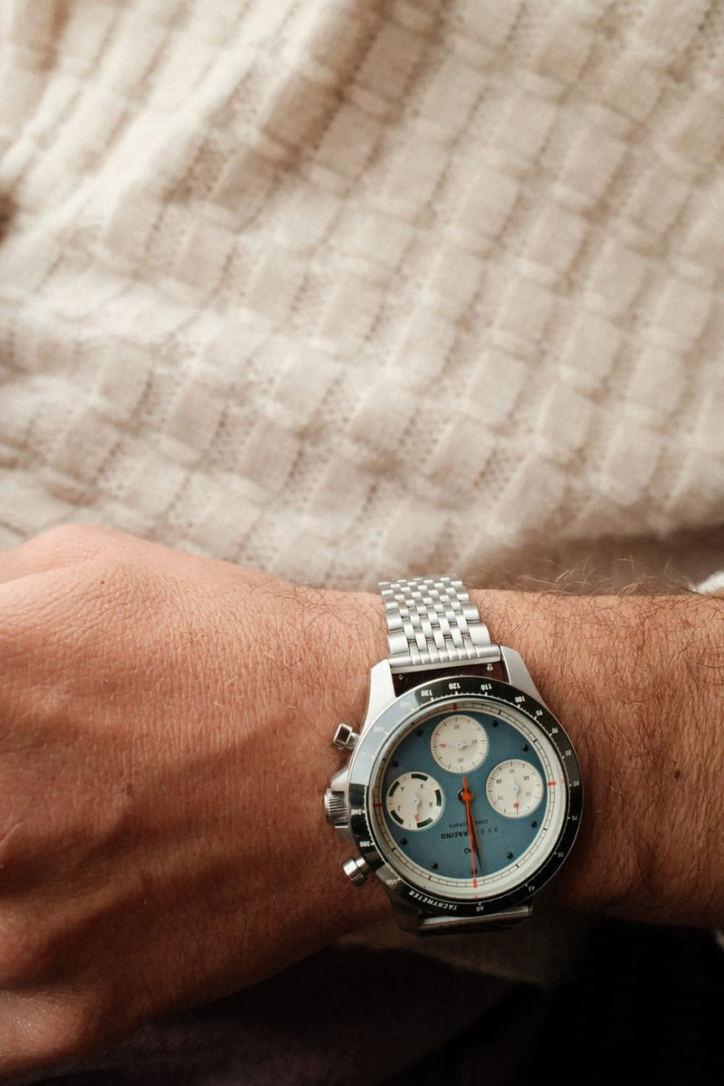 AV86 1960 Racing Chronograph, Steel / Sky Blue & Green quartz watch worn on the wrist with detailed subdials and stainless steel bracelet