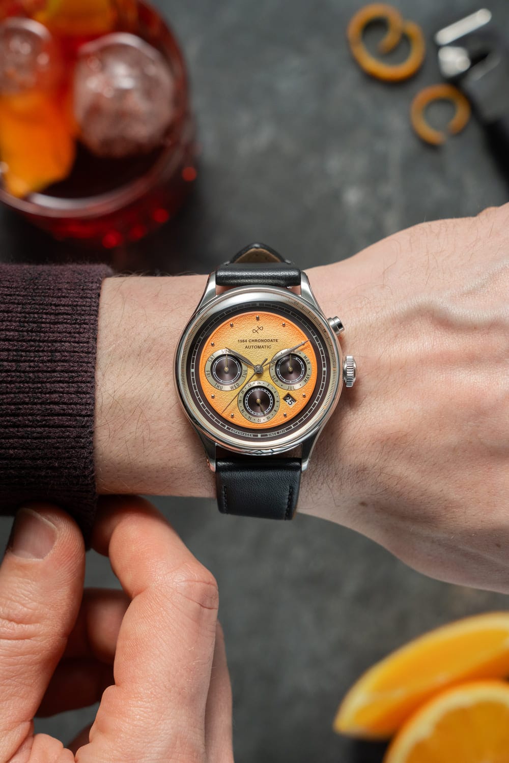 손목에 착용한 AV86의 1564 Chronograph 오토매틱: 빈티지 감성의 다이얼, Sapphire Crystal, 블랙 가죽 스트랩이 특징인 럭셔리 Chronograph