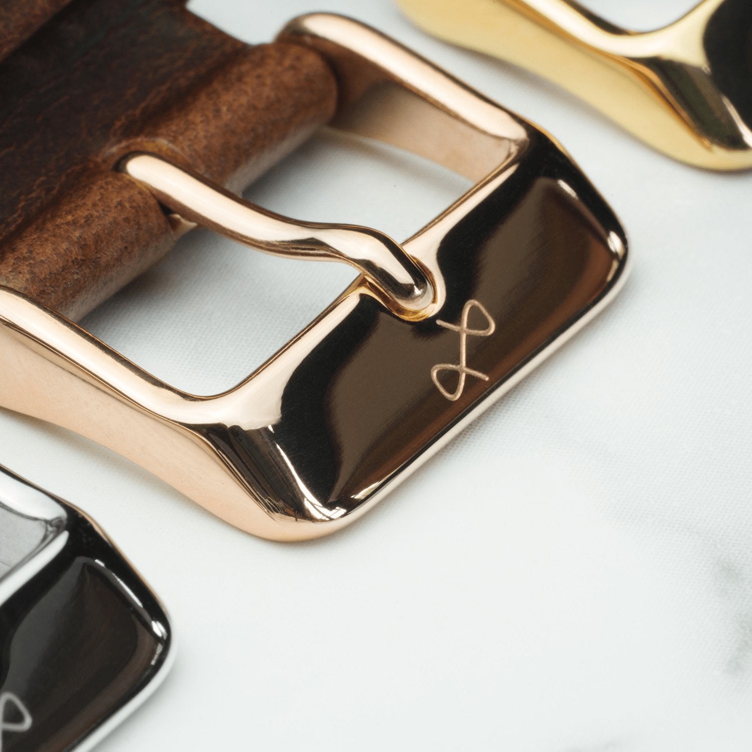 AV86의 스웨이드 - 블루 프리미엄 가죽 스트랩으로, 광택 처리된 로즈 골드 도금 핀 버클에 로고가 각인되어 있으며, 투피스 디자인입니다.