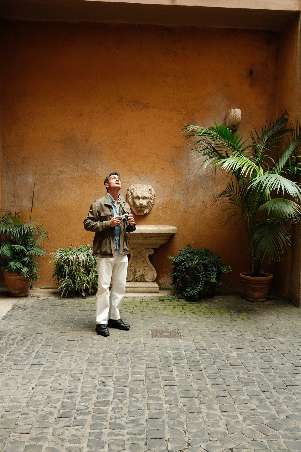 1954 Amalfi Mechanical by AV86 worn with layered casual attire in historic courtyard, evoking timeless Mediterranean elegance and exploration spirit