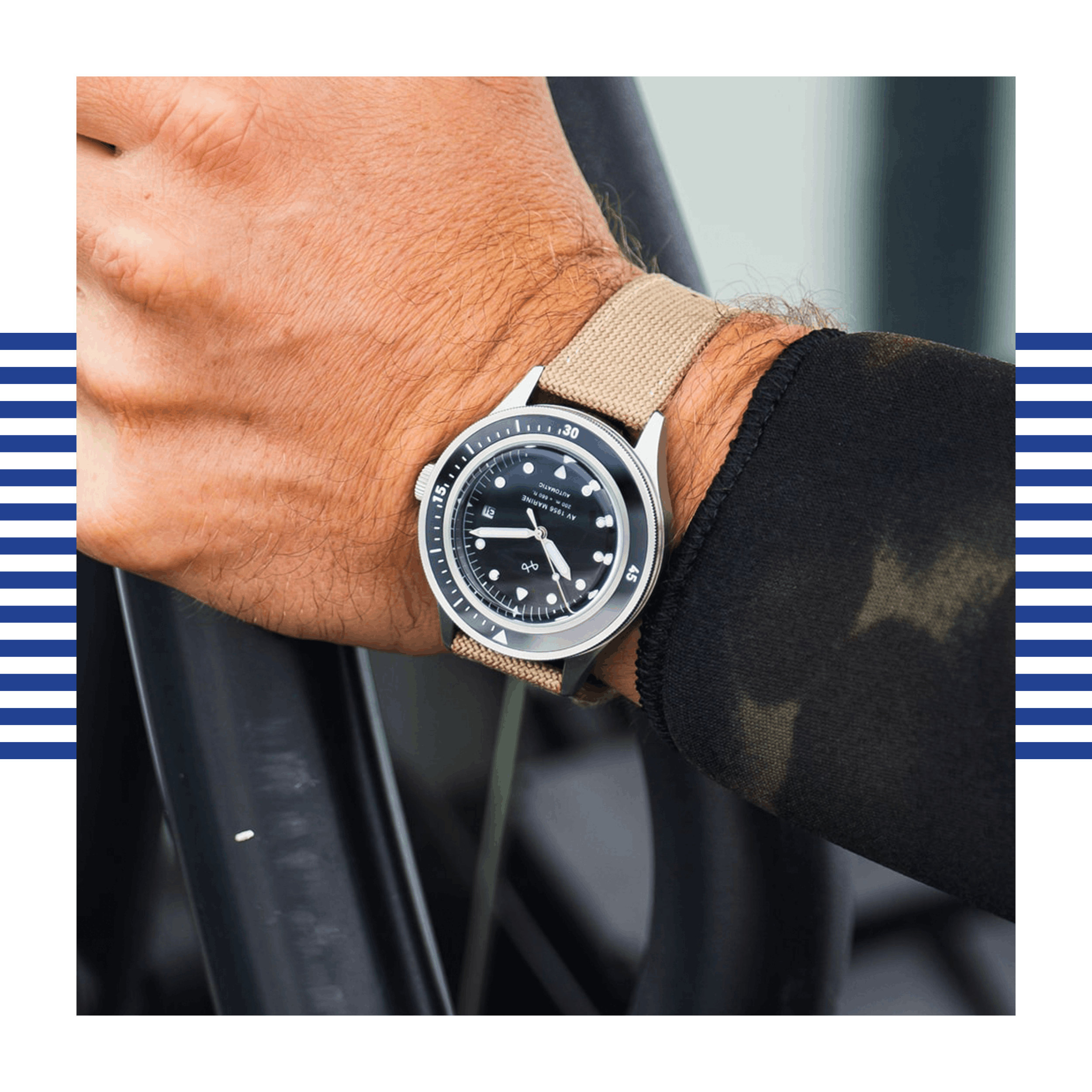 Wrist adorned with a stainless steel bezel watch featuring a black dial and beige textile strap on a dark sleeve.