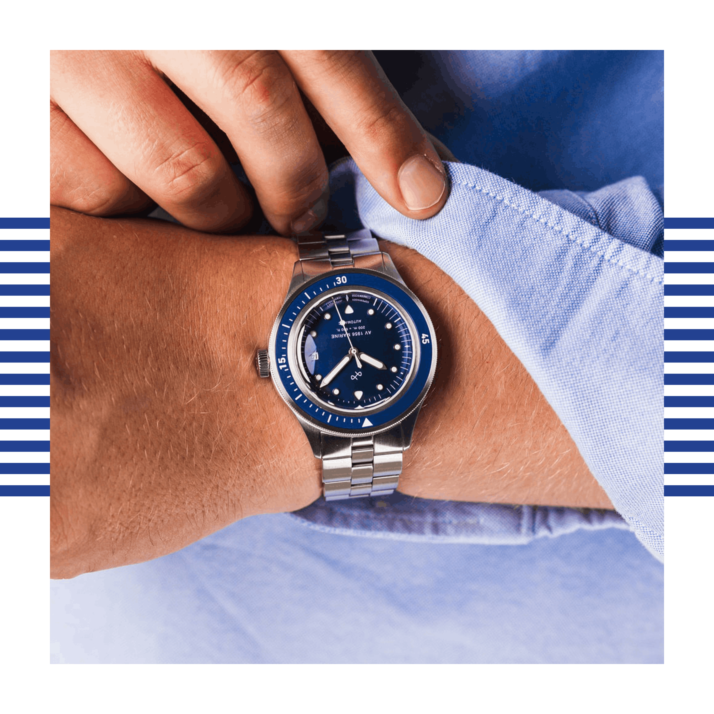 Wrist wearing a stainless steel watch with a deep blue dial and rotating bezel being adjusted over light blue shirt cuff.