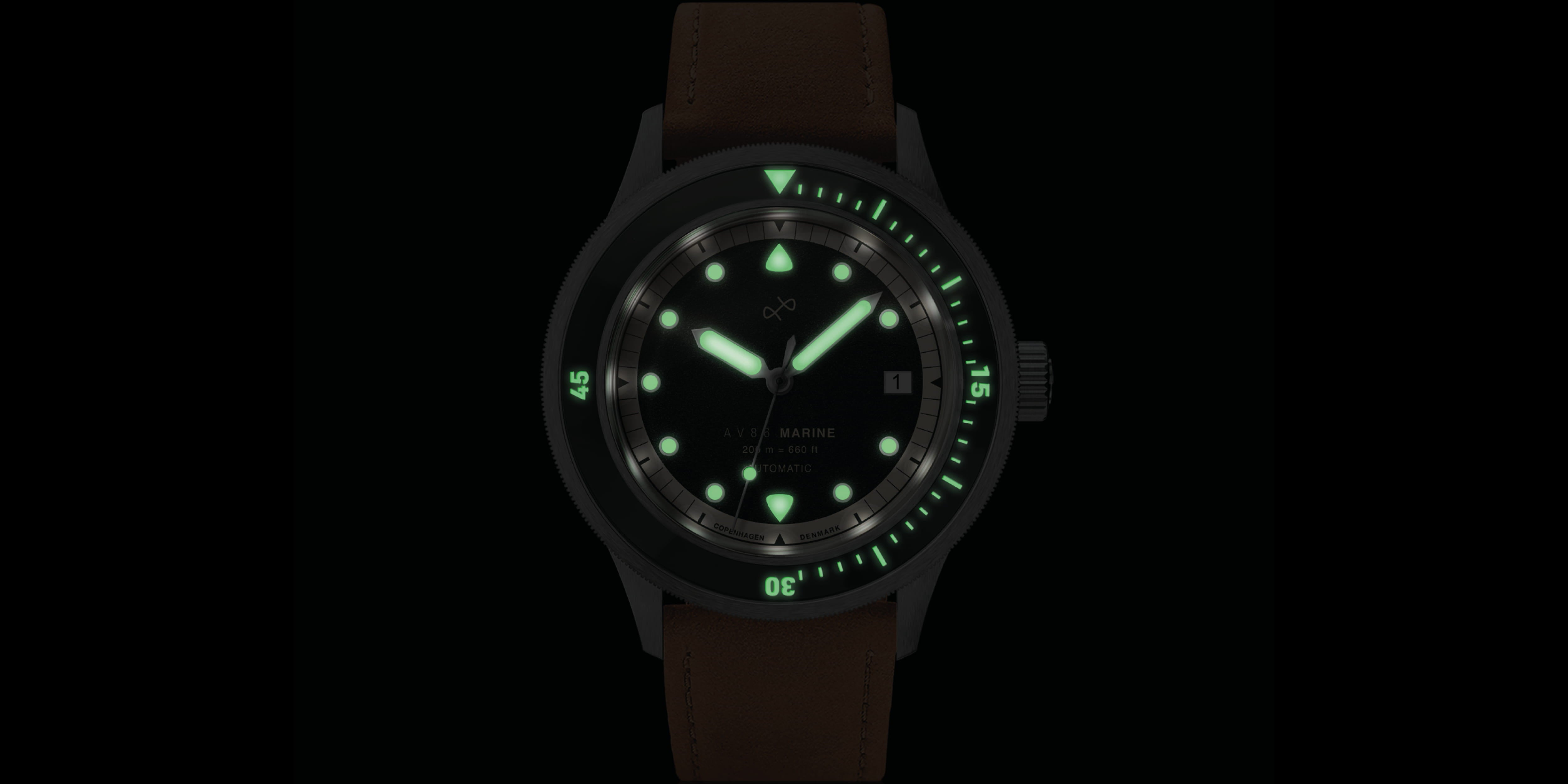Vintage-style diver wristwatch with glowing green luminescent hour markers, hands, and rotating bezel on a brown leather strap.