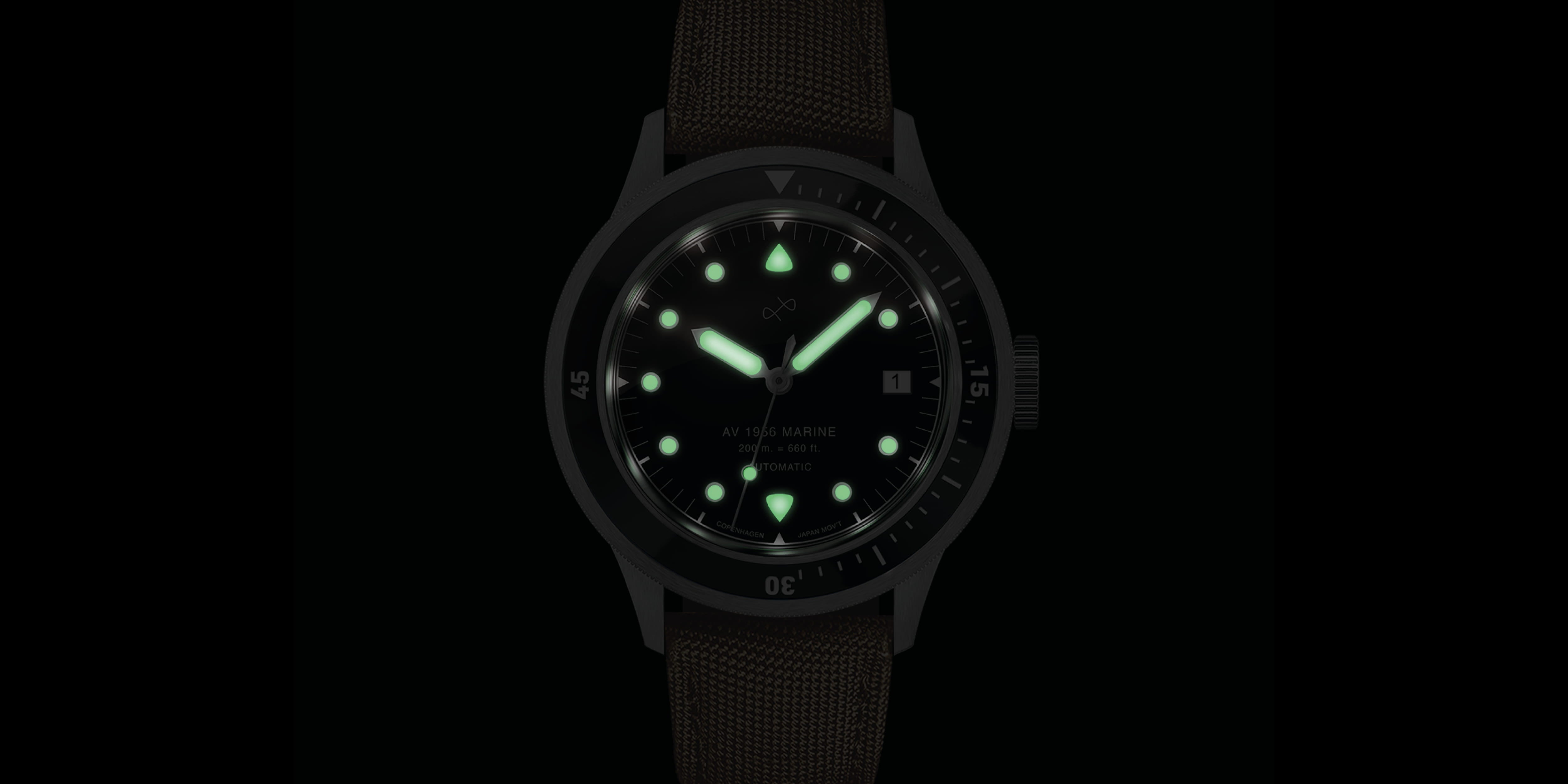 Luminous hands and hour markers glow bright green on a black dial wristwatch with a textured brown strap and rotating bezel.
