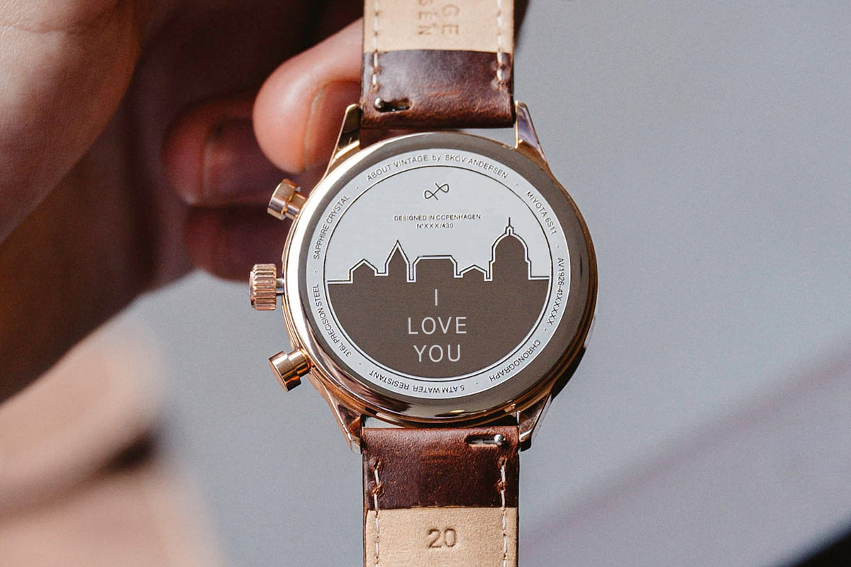 AV86 chronograph with engraving on case back featuring city skyline and "LOVE YOU" message, brown leather strap