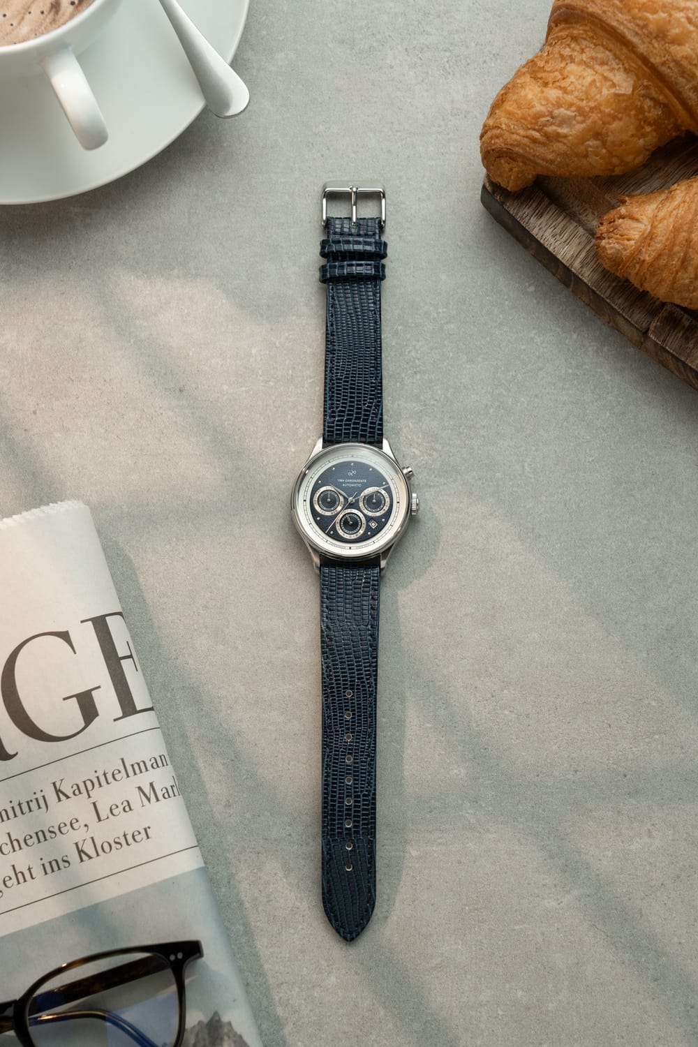1564 Chronodate Automatic by AV86 showcases a vintage-inspired automatic chronograph with a textured blue dial, triple subdials, date window, polished steel case, sapphire crystal, and a refined blue leather strap, reflecting Danish design and Nordic minimalism.