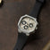 1904 Chrono, Steel / Off White & Black by AV86 featuring a stainless steel case, off-white dial with black chronograph subdials, black rubber strap, and sapphire crystal, resting on a dark brown leather surface evoking Scandinavian luxury and horological precision.