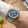 1564 Chronodate Automatic by AV86 featuring a textured ice blue dial with chronograph subdials, polished steel bracelet, and a sophisticated Scandinavian design on a wrist in a casual setting.