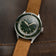 1956 Marine Automatic, Steel / Green vintage-inspired watch by AV86 with green dial and brown leather strap on dark surface