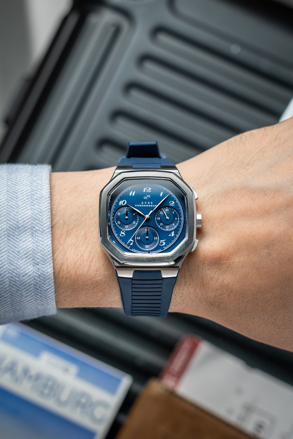 1904 Chronograph by AV86 with angular case, sapphire crystal, blue dial, three subdials, and blue rubber strap on wrist