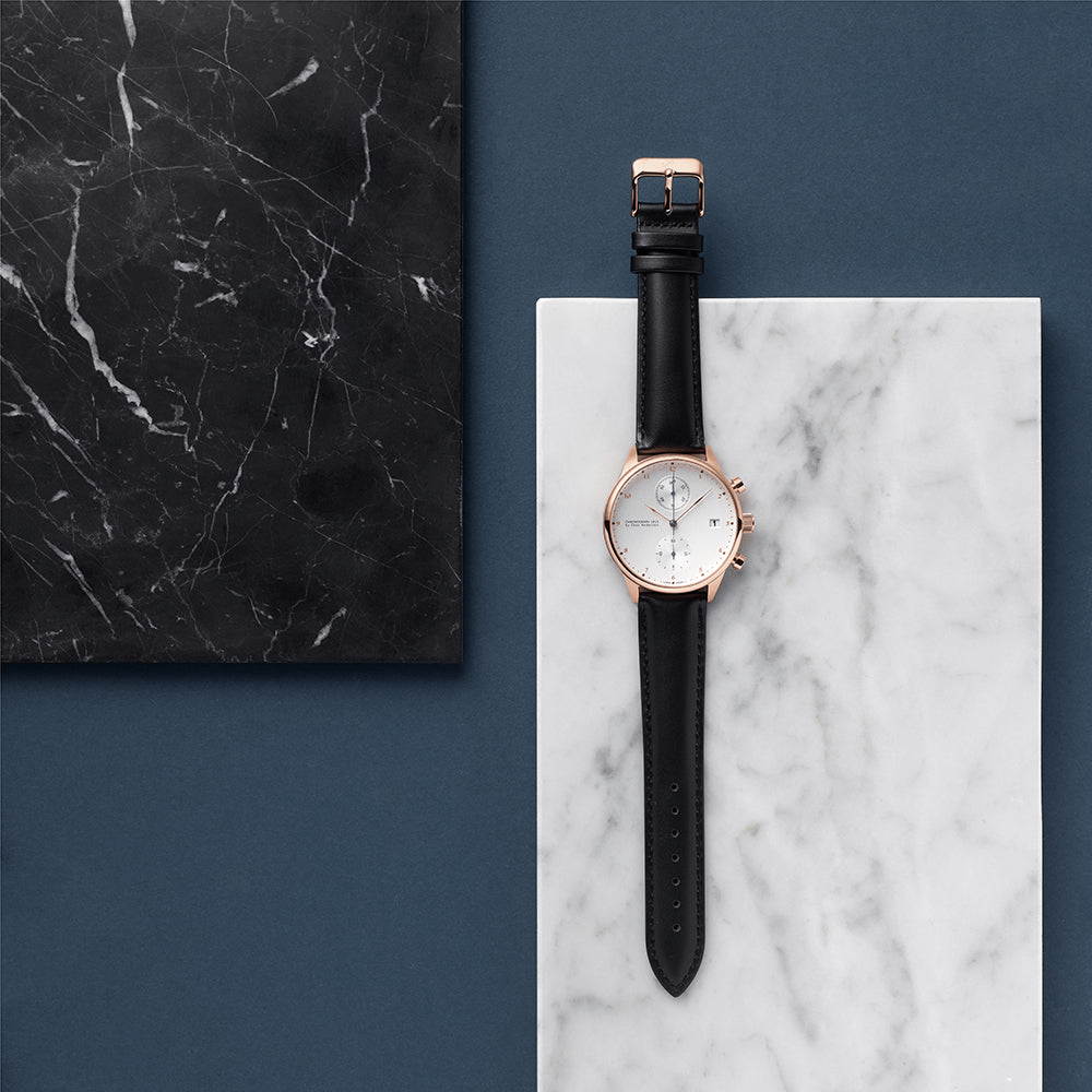 1815 Chronograph, Rose Gold / White by AV86 luxury chronograph with sapphire crystal, rose gold case, and black leather strap on marble background