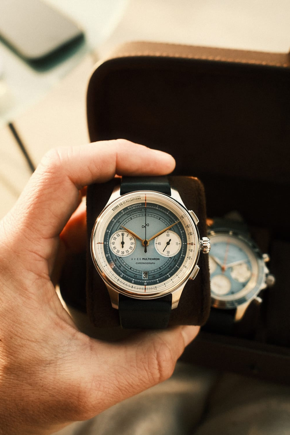 AV86 1934 Multichron, Steel / Sky Blue quartz chronograph with detailed dial and black leather strap held in an open watch case